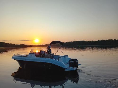a boat sitting on the water at sunset at Atpūtas vieta Ežezers in Andzeļi
