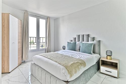 Un dormitorio blanco con una cama grande y una ventana en Appartement proche de Paris - Gagny, en Gagny