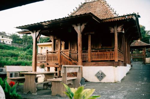 a house with a porch and benches in front of it at Tunjung Sari Villa Bedugul in Bedugul
