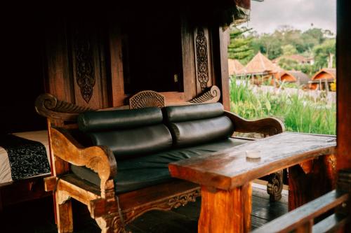 a green leather couch sitting on a wooden bench at Tunjung Sari Villa Bedugul in Bedugul
