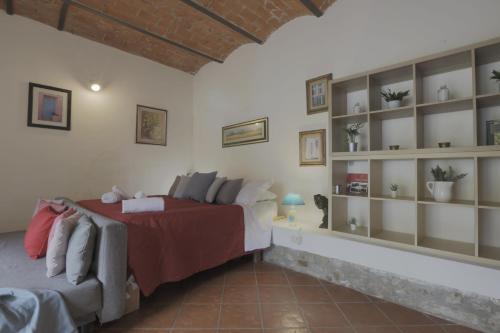 een slaapkamer met een bed en een bank en planken bij Fattoria la Luna 15 min da Firenze Bilocale la Stalla piscina e wi fi in Lastra a Signa