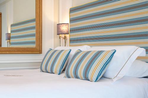a white bed with two striped pillows on it at Grand Hotel Capodimonte in Sorrento