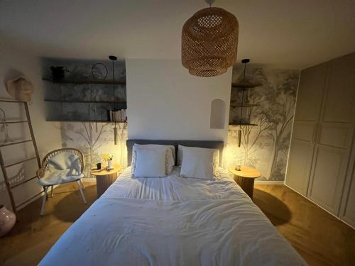 una camera da letto con un letto con lenzuola bianche e una sedia di Pool Villa 25 min from Paris a Yerres