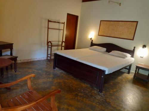 a bedroom with a bed and a chair and a table at Seetharama Garden of Life in Beruwala