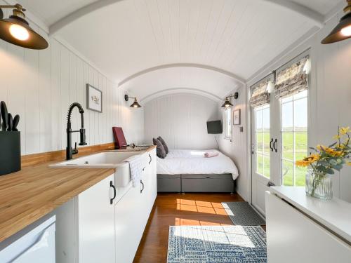 una cocina con fregadero y una cama en una habitación en Farm Shepherd's Hut, en Wendron