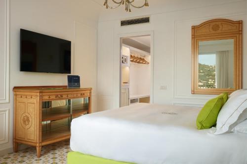 a bedroom with a white bed and a television at Grand Hotel Capodimonte in Sorrento