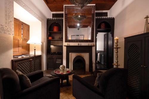 a living room with a fireplace and two chairs at La Villa Nomade in Marrakesh
