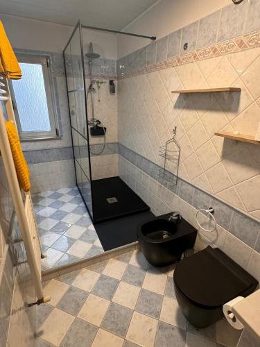 a bathroom with a black toilet and a shower at Casa di Giovanni - Italien in Muggia