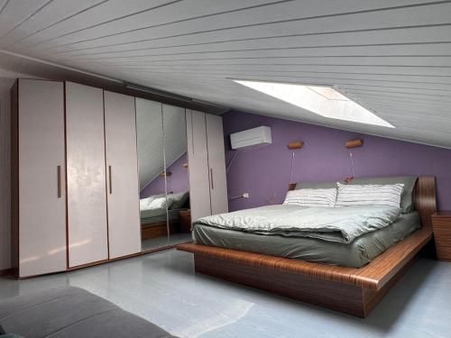 - une chambre avec un lit et un mur violet dans l'établissement Casa di Giovanni - Italien, à Muggia