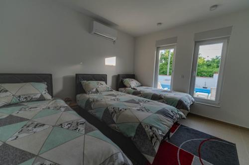 two beds in a room with two windows at Villa Green in Mostar