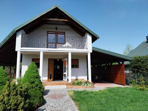 a white house with a balcony on top of it at Domek Chmiel I nad Jeziorem Tarnobrzeskim in Chmielów