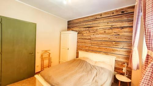 a bedroom with a wooden wall and a bed at Lovely Alps ski apartment on Alpe Adria bike trail in Pontebba