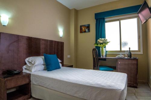 a bedroom with a bed and a desk and a window at Hotel Aeropuerto Sur in San Isidro