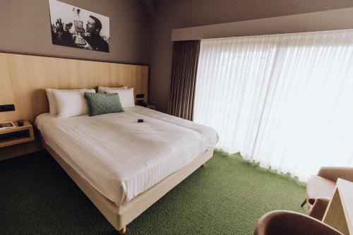 een slaapkamer met een groot bed en een groot raam bij Hôtel Five Nations in Durbuy