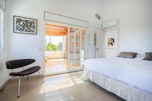 - une chambre avec un grand lit et une chaise dans l'établissement Villa Alzina en montemar, à Castelldefels