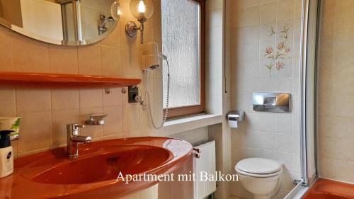 a bathroom with a red sink and a toilet at Hotel-garni-Kachelburg in Dieblich