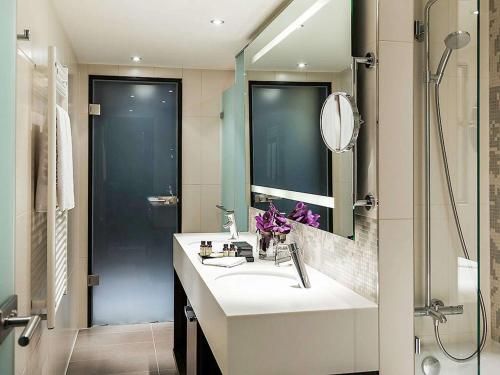 a bathroom with a sink and a shower at Pullman Munich in Munich