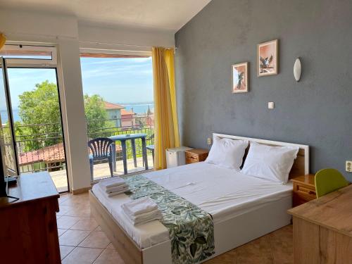 a bedroom with a large bed and a balcony at Guesthouse Serenity hill in Sveti Vlas