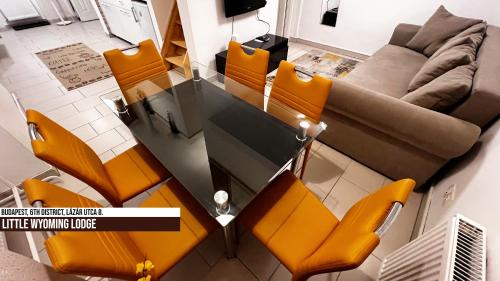 a dining room table with orange chairs and a couch at Little Americas Wyoming Lodge Apartment in Budapest