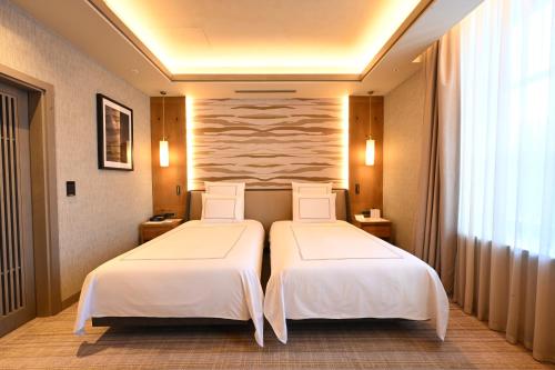 two beds in a hotel room with white sheets at Swissotel Uludag Bursa in Bursa
