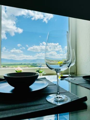 a table with a wine glass on a table with a window at Apartman Latice in Tomislavgrad