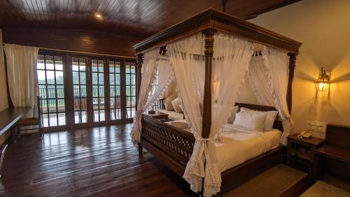 a bedroom with a canopy bed with white curtains at Ayara Coorg Resort and Spa in Virajpet