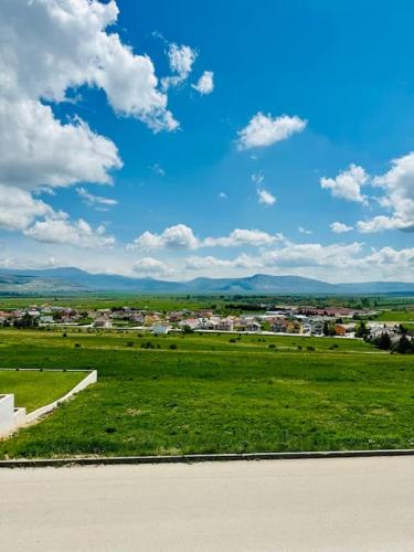 a field of green grass with a city in the background at Apartman Latice in Tomislavgrad
