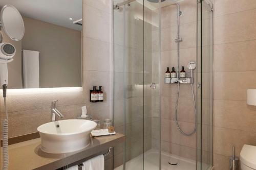 a bathroom with a sink and a glass shower at NH Berlin Kurfürstendamm in Berlin