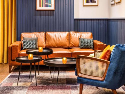 a living room with a leather couch and two tables at ibis Styles London Gloucester Road in London
