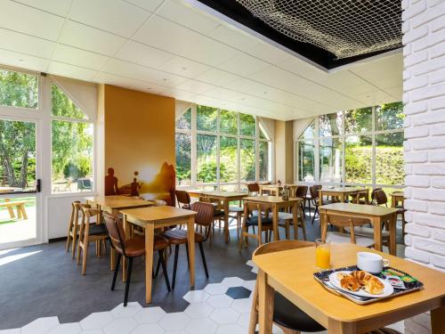 un restaurante con mesas, sillas y ventanas en Ibis Styles Bobigny Centre Préfecture, en Bobigny