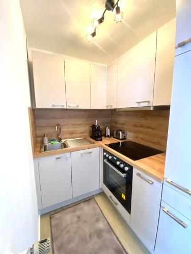 una cocina con armarios blancos y fregadero en Komfortable Wohnung in zentraler Lage, en Ingolstadt