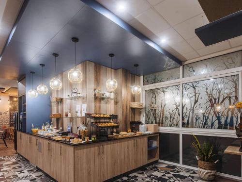 a restaurant with a counter with lights on the wall at ibis Styles Ancenis Centre in Ancenis