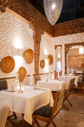 a restaurant with white tables and chairs and a chandelier at La Villa Nomade in Marrakech