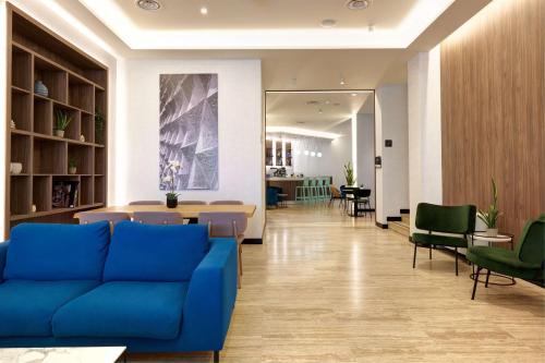 a lobby with a blue couch and tables and chairs at Radisson Hotel Ferrara in Ferrara