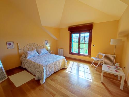 a bedroom with a bed and a table and a window at Casa de campo en Ribadeo in Ribadeo
