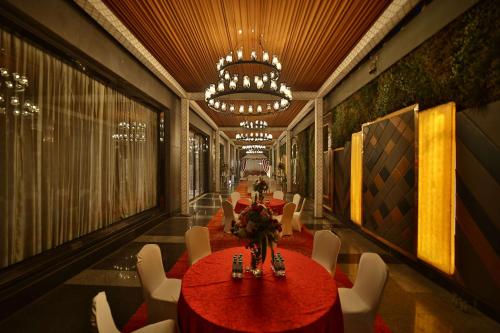 a room with tables and white chairs and a chandelier at Radisson Blu Towers Kaushambi Delhi NCR in Ghaziabad