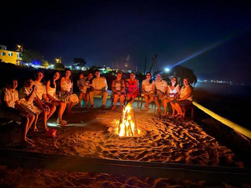 a group of people sitting around a fire on the beach at La Fogata in Machalilla