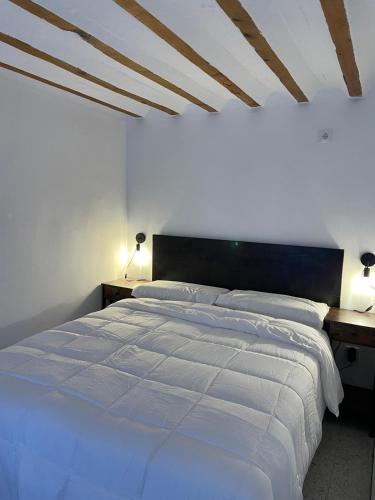 a bedroom with a large white bed with two lamps at La casita Azul in Cazorla