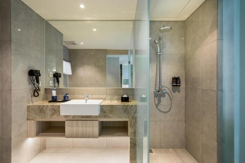 a bathroom with a sink and a shower at Aston Bintaro Hotel & Conference Center in Kampungutan
