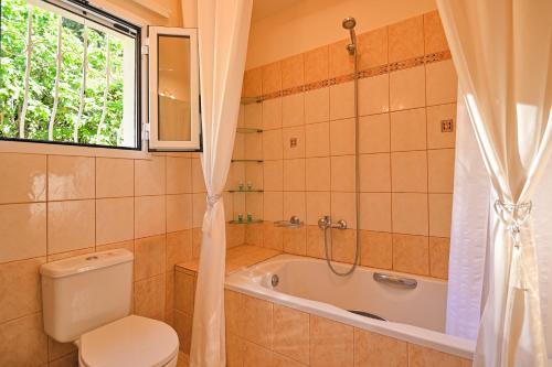 a bathroom with a toilet and a tub and a window at Villa Seasunrise in Perama