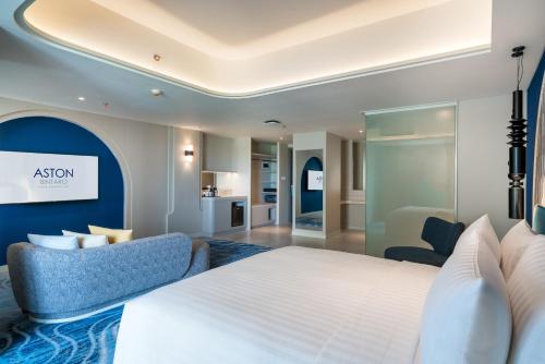 a bedroom with a white bed and a blue couch at Aston Bintaro Hotel & Conference Center in Kampungutan