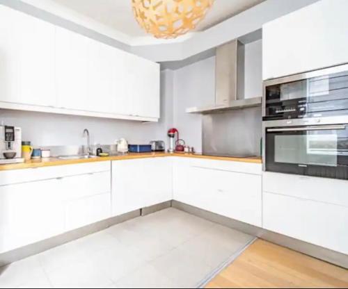Una cocina blanca con gabinetes blancos y un fregadero. en lumineux havre de paix à 6 minutes de Paris, en Maisons-Alfort