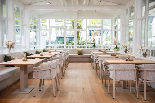 una fila di tavoli e sedie in un ristorante con finestre di Apollo AchtQuartier Das Hotel am Mondsee a Mondsee