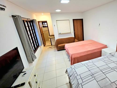 um quarto de hotel com duas camas e uma televisão de ecrã plano em Flor de Lótus Suites em Tamandaré