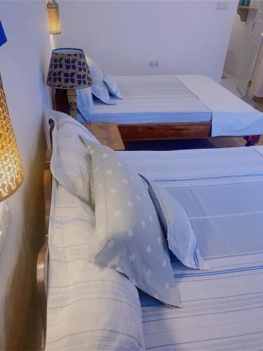 two twin beds in a room with a lamp at Casa Carlotta & Villa in Nungwi