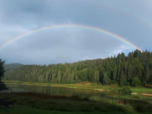 un arco iris sobre un lago y un bosque en Le Chalet, en Lamoura