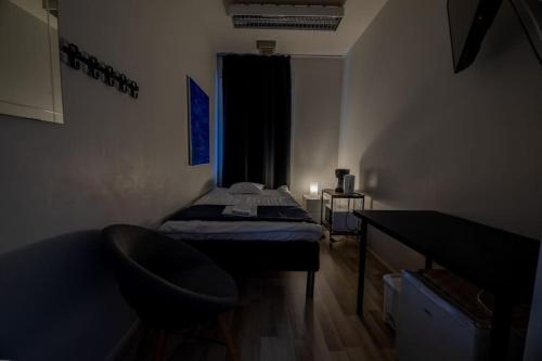 a small room with a bed and a chair at Budget City room Self check-in Vanha Postitalo in Varkaus