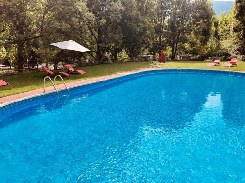 a large blue swimming pool with an umbrella and chairs at Camping Aigües Braves in Llavorsí