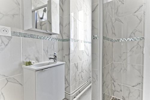 une salle de bain blanche avec un lavabo et une douche dans l'établissement Appartement paisible et moderne - Gagny, à Gagny