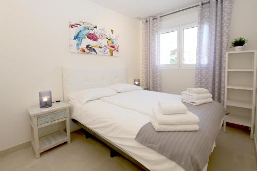 biała sypialnia z łóżkiem i oknem w obiekcie Apartment BEATRIX w mieście Estepona
